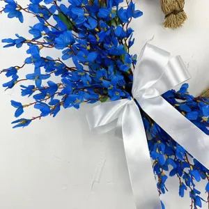Detail view of heart-shaped blue artificial flower wreath with elegant white satin bow