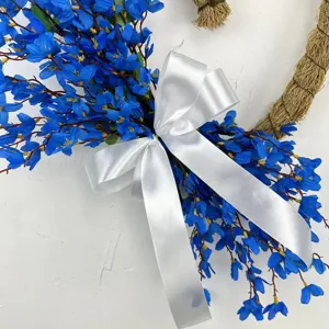 Close-up detail of artificial blue jasmine wreath with elegant white satin bow
