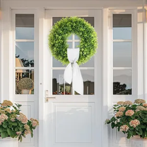 Vibrant artificial green boxwood wreath with a classic white bow for front door decoration