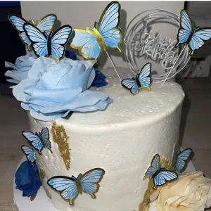 Detail von blauen Aquarell-Schmetterlings-Kuchendekorationen mit Goldrand auf einer Torte.
