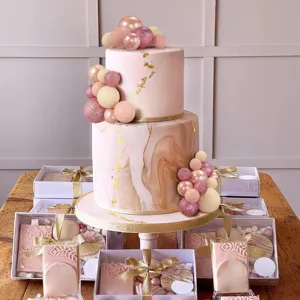 32-piece set of pink and rose gold cake decoration balls arranged on a marble cake