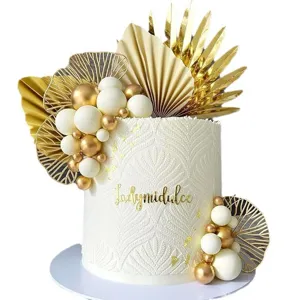Champagne gold cake topper set with white decorative balls and palm leaves for boho party.