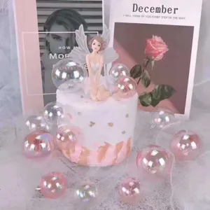 Dettagli delle palline trasparenti iridescenti per torta e statuetta fata per festa.