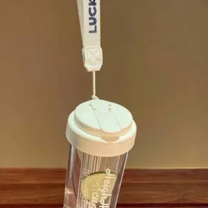 Portable clear plastic straw water cup with a white lid and luck strap handle