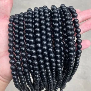 Detailed close-up of multiple strands of shiny black glass beads for DIY jewelry making