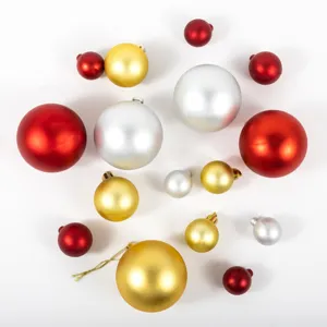 Assortimento di palline di Natale festive in rosso, oro e argento su sfondo bianco