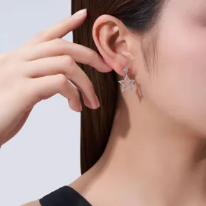 Détail de boucles d'oreilles étoile en argent S925 portées à l'oreille, look élégant