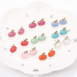 Multi-colored enamel pumpkin stud earrings displayed on a white decorative plate