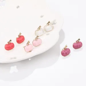 Macro view of various colored enamel pumpkin stud earrings for Halloween and Thanksgiving.