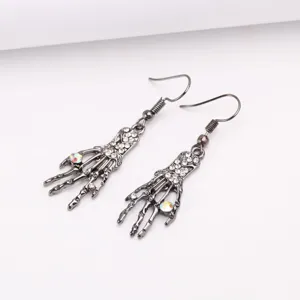 Detalle macro de pendientes colgantes de mano de esqueleto para Halloween con strass brillante.