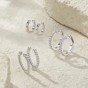 Detailed view of three styles of S925 silver C-shape ear cuffs on stone background