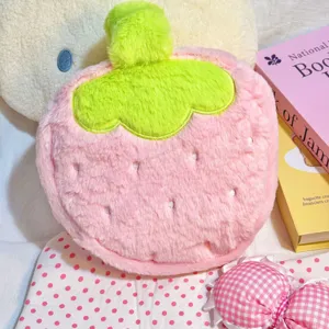 Close-up detail of a cute pink plush strawberry-shaped makeup bag with soft green leaf decor