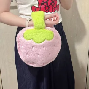 Cute plush strawberry makeup bag in soft pink and green, shown being held by a hand
