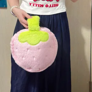 Close-up of a cute pink plush strawberry-shaped cosmetic storage bag being held by hand