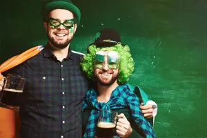Feestelijke mannen vieren St. Patrick's Day met groene hoeden, pruiken en bierglazen.