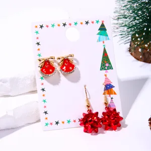Detailed macro view of festive red bell and bow Christmas earring set on display card