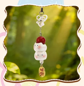 Gros plan d'un mignon pendentif chat en céramique avec une étiquette dorée porte-bonheur.