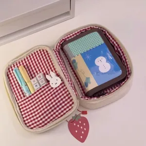 Vista dettagliata della borsa sandwich aperta con interno a quadri rossi e articoli di cancelleria.