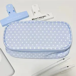 Vista dettagliata di un astuccio a pois blu con accessori di cancelleria bianchi.