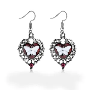 Detailed macro view of vintage silver heart-shaped earrings with white butterfly motif