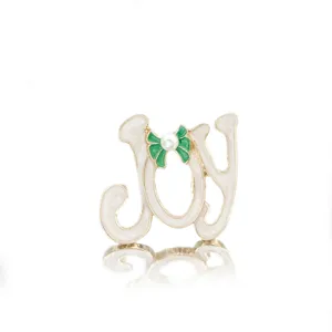 Close-up of festive JOY Christmas brooch featuring a green bow and elegant pearl detail
