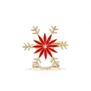 Macro view of Christmas snowflake brooch with vibrant red enamel and gold finish