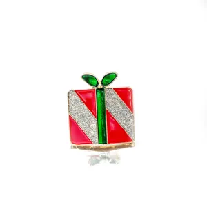 Macro view of Christmas gift box brooch with red and green enamel and silver glitter