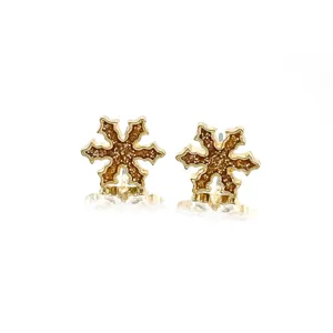 Detail of golden snowflake stud earrings with brown glitter drip oil finish