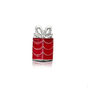A detailed macro view of a festive red enamel gift box brooch with a silver bow