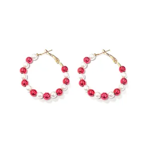 Close-up macro detail of red and white bead hoop earrings with gold-toned metal