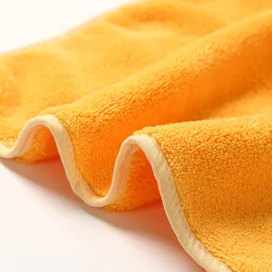 Macro detail of soft yellow coral fleece hand towel, showing plush texture and bound edge.