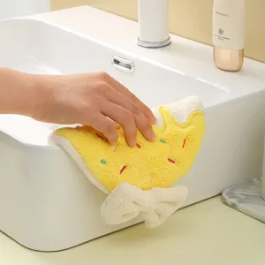 Detail view showing yellow doughnut-shaped coral fleece hand towel wiping a white sink