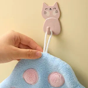Close-up detail of soft coral fleece hanging hand towel with cute cartoon cat hook on wall.