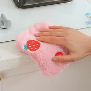 Close-up view of a cute pink coral fleece strawberry embroidered hand towel in kitchen setting.