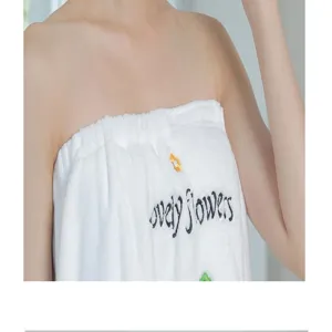 Detailed view of white coral fleece wearable bath towel with cute embroidery and soft texture.