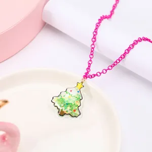 Vue détaillée d'un collier rose pour enfant avec pendentif sapin de Noël à paillettes