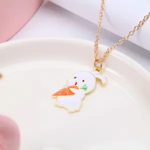 Detail of gold chain necklace with a cute white enamel rabbit holding a carrot pendant.
