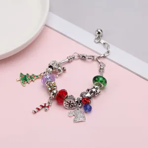 Detalle de pulsera de dijes navideños con árbol, bastón de caramelo y cuentas de colores.
