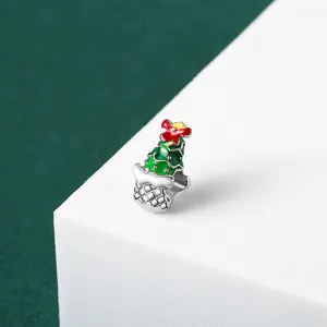 Detailed view of a green enamel Christmas tree charm bead with a red bow on top