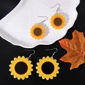 Detailed view of vibrant yellow sunflower acrylic earrings on white shell tray and black background