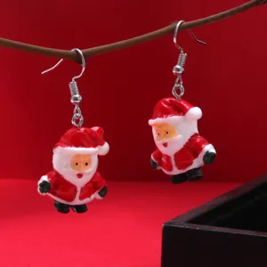 Close-up detail of adorable cartoon Santa Claus resin earrings hanging on a twig