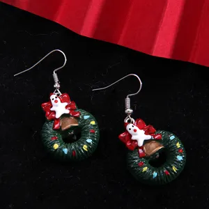 Detailed close-up of festive Christmas wreath drop earrings with red bow and bell