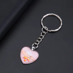 Close-up detail van een hartvormige sleutelhanger met LOVE-print en handafbeelding.