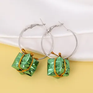Detailopname van feestelijke zilveren creolen met groene metallic geschenkdoos hangers