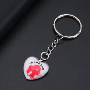 Detail van een hartvormige sleutelhanger met rood silhouet en de tekst thank you.