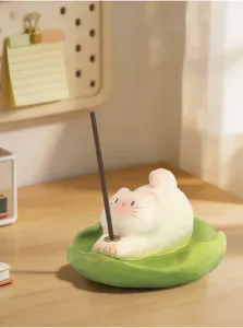 Vue détaillée d'une figurine de chat blanc servant de porte-encens sur un bureau