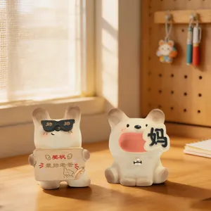 Adorable cartoon resin cat and dog figurines displayed on a warm sunlit wooden office desk