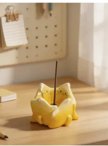 Vue détaillée d'un porte-encens en céramique chat jaune sur un bureau avec un bâton