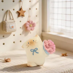 Detailed close-up of a cute resin cat figurine holding a pink flower with a blue bow