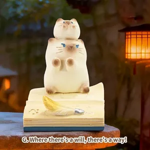 Détail d'une adorable figurine de chat en résine posée sur un support de livre décoratif